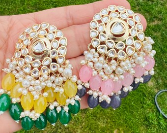 May include: A pair of gold earrings with intricate designs and dangling beads. The earrings feature a round, multi-faceted center stone surrounded by smaller stones. The beads are in shades of green, yellow, pink, and blue.