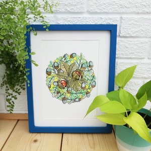 May include: A framed illustration of a circle of autumn leaves and acorns with a cluster of chestnuts in the centre. The leaves are green, yellow, and brown, and the acorns are blue and brown. The chestnuts are brown with red accents.