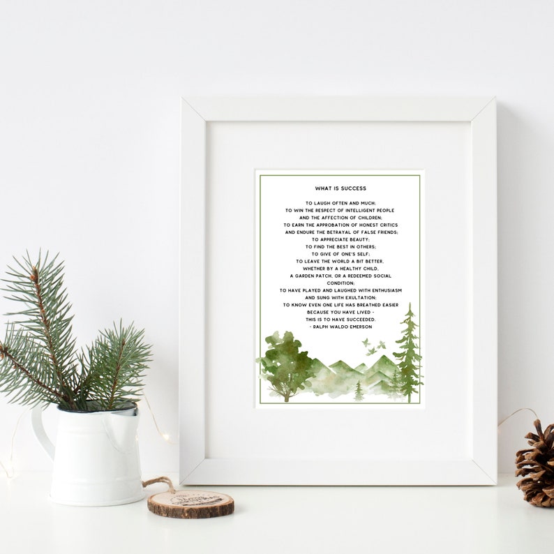 Op de afbeelding: Een ingelijst afdruk met een groene aquarel achtergrond met een bergketen en bomen. De afdruk bevat een citaat van Ralph Waldo Emerson over succes, dat luidt: "Vaak en veel lachen... Dat is succesvol zijn."