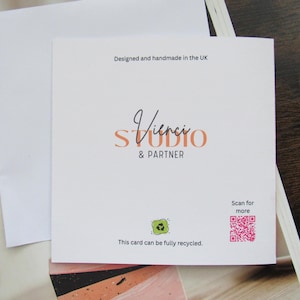 May include: A white card with the text "Vinci STUDIO & PARTNER". The card also includes the text "Designed and handmade in the UK", a QR code, and a recycling symbol. The card is fully recyclable. The card is accompanied by a white envelope.
