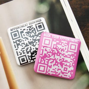 Puede incluir: Dos pegatinas cuadradas de código QR. Una es en blanco y negro con el texto "APPOINTMENT BOOKINGS". La otra es rosa con el texto "BOOK YOUR APPOINTMENT".