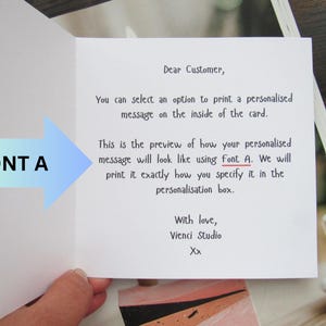 May include: An open greeting card with text explaining how a personalised message will appear using Font A. The card is white with black text and a blue and green arrow pointing to the text.