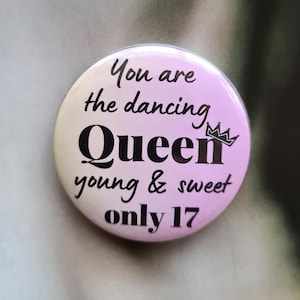 May include: Pink and white button with the text "You are the dancing Queen young & sweet only 17" and a crown graphic.