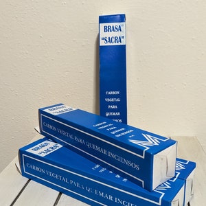 Puede incluir: Tres cajas azules apiladas una encima de la otra. Las cajas están etiquetadas "Brasa "Sacra" Carbon Vegetal Para Quemar Inciensos".
