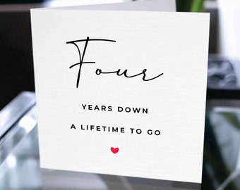 May include: A white card with black text that reads "Four Years Down A Lifetime To Go" with a small red heart at the bottom.