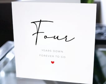 May include: A white card with black text that reads "Four Years Down Forever To Go" with a small red heart symbol below the text.
