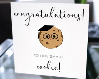 May include: A white card with the text "congratulations!" in black cursive writing. A cartoon cookie wearing a graduation cap and glasses is above the text. Below the cookie is the text "to one smart cookie!"