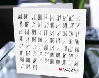 May include: A white card with a grid of 100 tally marks, each row containing 10 marks. The card has a red heart and the date 06.20.2022 written in black ink.