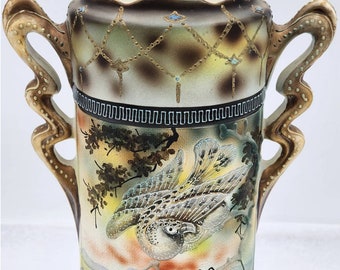 May include: A ceramic vase with a brown, gold, and blue floral design. The vase has two handles and a wide mouth.