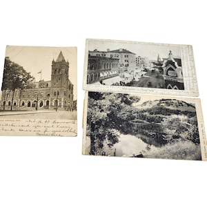 May include: Three vintage black and white postcards. The first postcard shows a building with a clock tower and the text "Post Office". The second postcard shows a street scene with the text "Main Street, La Crosse, Wis". The third postcard shows a lake scene with the text "Lake Como, near La Crosse, Wis".