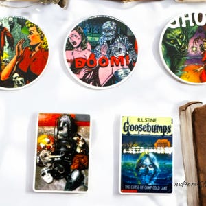 May include: A collection of vintage-style horror-themed stickers and a Goosebumps book cover. The stickers feature comic book art of monsters and scenes with the word "BOOM!" and "GHOSTS". The book is titled "Goosebumps" and "The Curse of Camp Cold Lake".