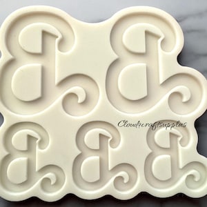 May include: Off-white silicone mold featuring four stylized ampersand (&) symbols. The ampersands have a classic, elegant design with a rounded serif font and decorative swirls. The text "Cloudcraftsupplies" is printed on the mold.