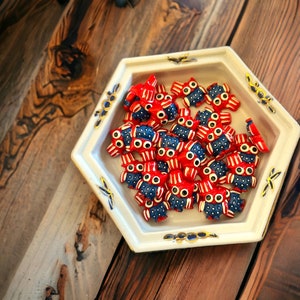 May include: A white ceramic dish with a hexagonal shape and a blue and gold design holds a collection of small, red and blue ceramic owls. The owls have a whimsical, cartoon-like appearance.