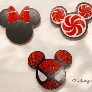 May include: Three red and black mouse-shaped resin ornaments. One ornament features a red bow, one features a red and white candy cane design, and one features a red and black spider-man design.