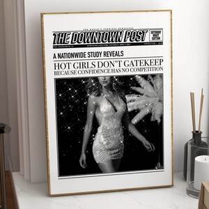 May include: A framed poster titled The Downtown Post featuring a black and white photograph of a person in a sequined dress. The headline reads A NATIONWIDE STUDY REVEALS HOT GIRLS DON'T GATEKEEP BECAUSE CONFIDENCE HAS NO COMPETITION in bold text.