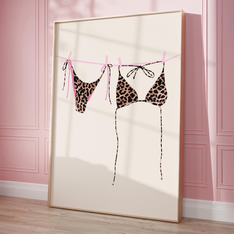 May include: A leopard print bikini hanging on a clothesline with pink string. The bikini is made of a soft, stretchy fabric and has a classic triangle top and a cheeky bottom.