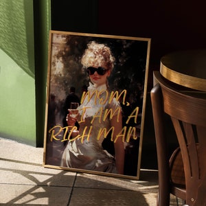 May include: A framed print of a woman wearing sunglasses and a white dress, holding a glass of wine. The text "MOM, I AM A RICH MAN" is written in gold lettering on the print.