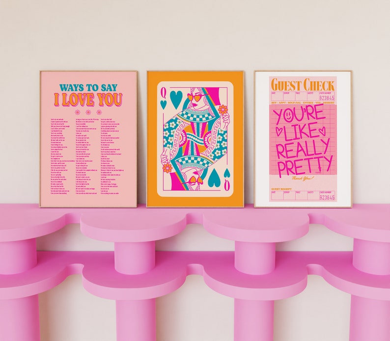 May include: Three framed prints with a pink, orange, and yellow background. The first print says "Ways to Say I Love You" and has a list of phrases. The second print features a queen of hearts playing card with a woman wearing sunglasses and a crown. The third print says "Guest Check" and has the text "You're Like Really Pretty" in pink and red.