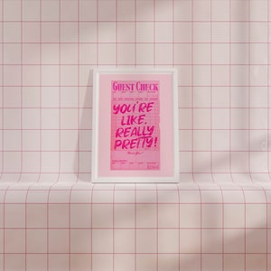 May include: A white framed print with a pink background and the text "GUEST CHECK" at the top. The text "YOU'RE LIKE REALLY PRETTY!" is written in pink on a white background. The text "Thank You!" is written in black at the bottom of the print.