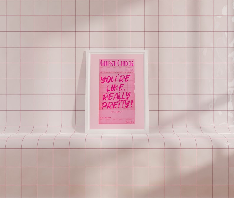 May include: A white framed print with a pink background and the text "GUEST CHECK" at the top. The text "YOU'RE LIKE REALLY PRETTY!" is written in pink on a white background. The text "Thank You!" is written in black at the bottom of the print.