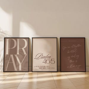 May include: Three framed art prints with inspirational quotes. The first print says "PRAY" in large, bold letters. The second print features "Psalm 46:5" and the text "GOD IS WITHIN HER, SHE WILL NOT FALL". The third print says "You are altogether beautiful, my darling, there is no flaw in you".