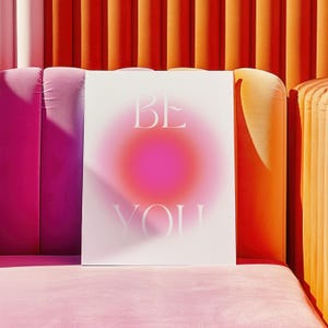 Peut inclure: Une affiche blanche avec un fond d&eacute;grad&eacute; rose et orange. Le texte "BE YOU" est imprim&eacute; en blanc sur l'affiche.