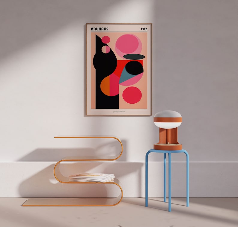 May include: A gold metal side table with a curved design and three shelves. A white lamp with a brown base sits on a blue stool next to the table. A framed poster with the text "BAUHAUS 1923" and a geometric design in red, pink, blue, and black hangs on a white wall.