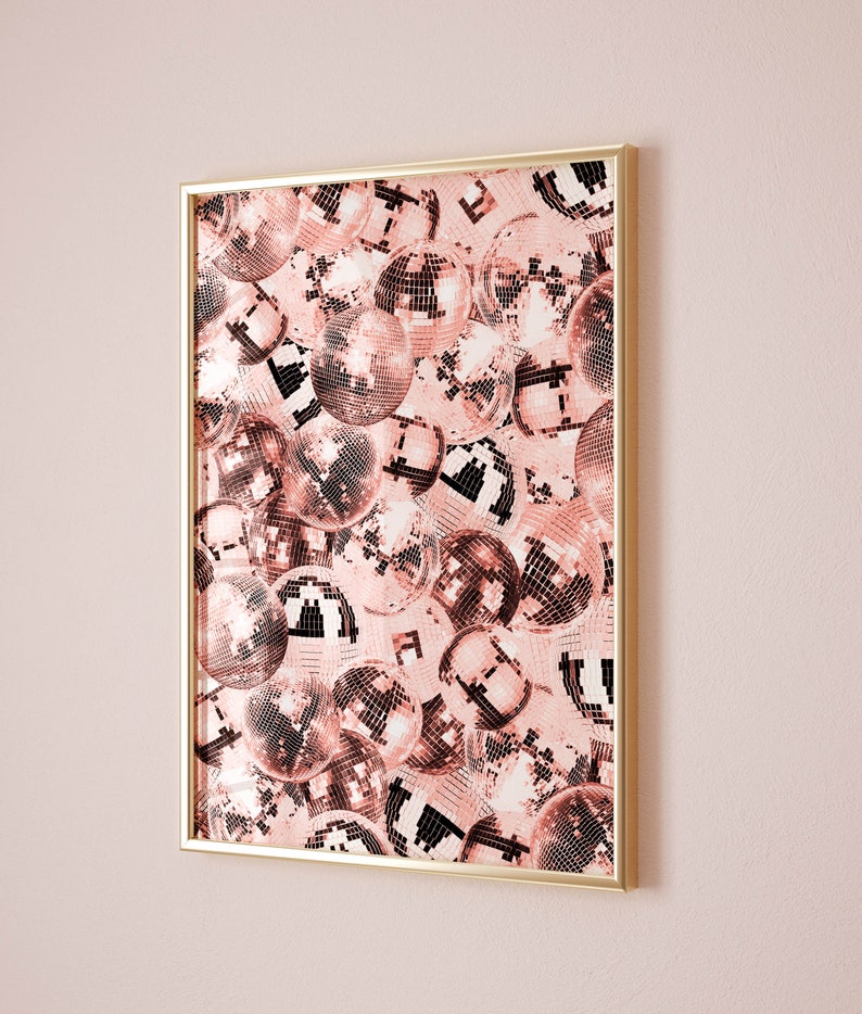 May include: A framed print of a pink and white disco ball pattern. The disco balls are arranged in a random pattern and overlap each other. The frame is gold.