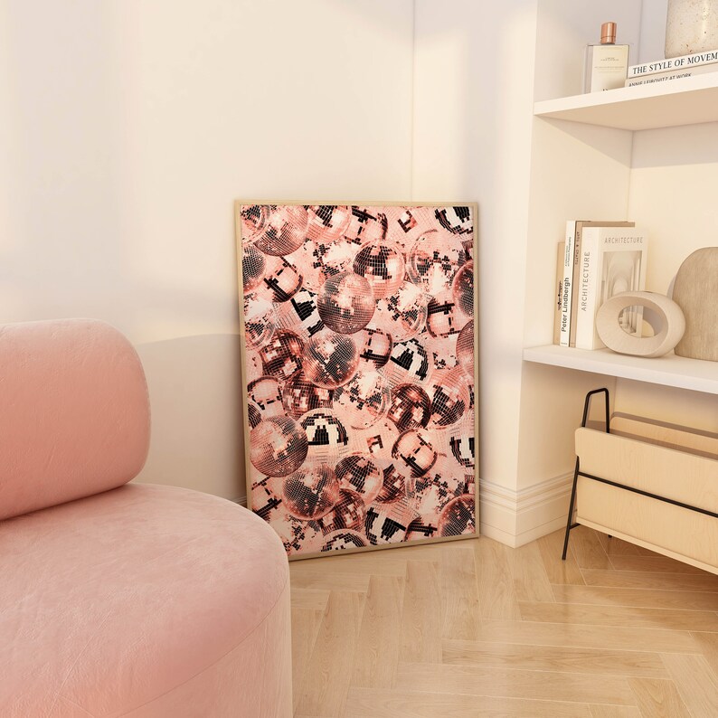 May include: A framed print of a pink and black disco ball pattern. The print is hanging on a white wall in a room with a pink armchair.