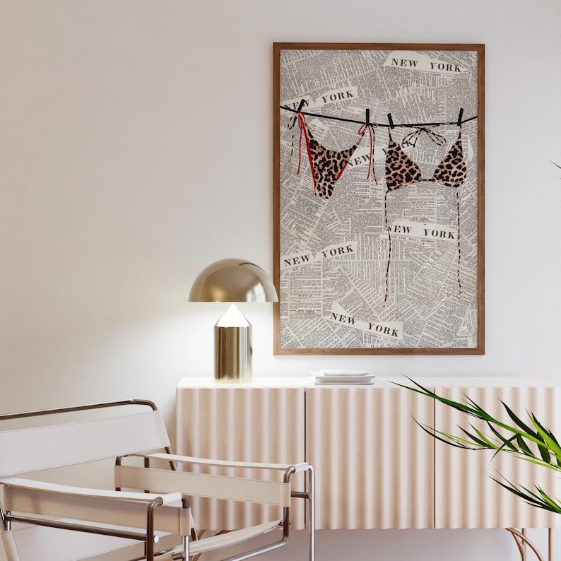 May include: A framed print of a leopard print bikini hanging on a clothesline against a background of a newspaper with the words "NEW YORK" repeated throughout.