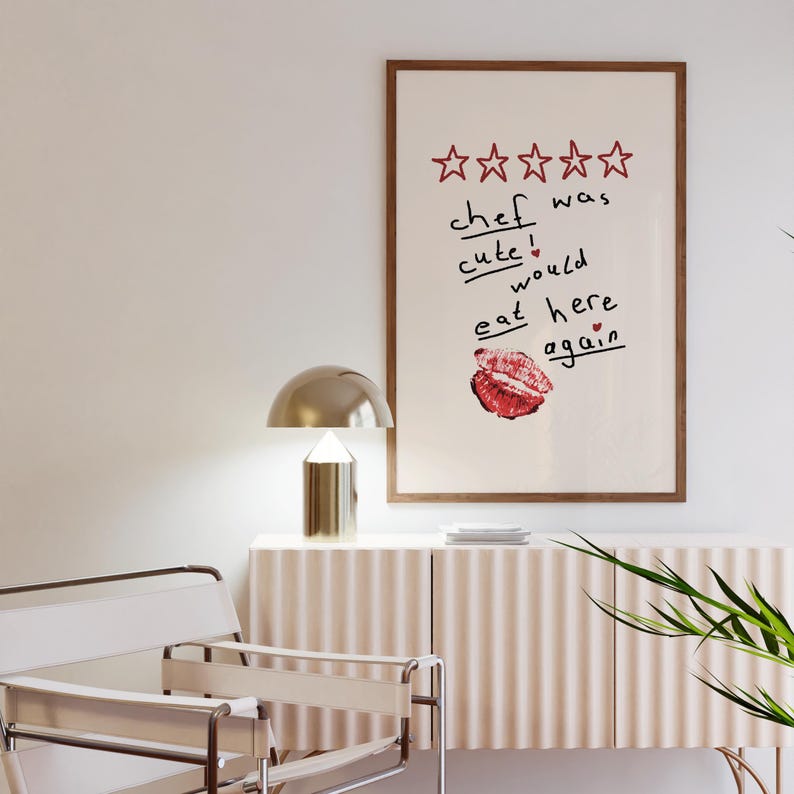 Op de afbeelding: Een ingelijst print met een vijfsterrenbeoordeling en de tekst "kok was schattig! zou hier weer eten" met een rode lippenstiftkus.
