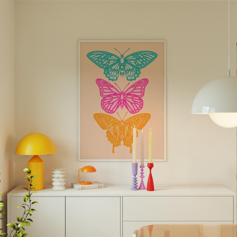 Pode incluir: Uma impress&atilde;o emoldurada com tr&ecirc;s ilustra&ccedil;&otilde;es de borboletas coloridas. As borboletas est&atilde;o sobrepostas, com uma borboleta turquesa no topo, uma borboleta rosa no meio e uma borboleta laranja na parte inferior. As borboletas s&atilde;o delineadas em preto e t&ecirc;m um fundo branco.