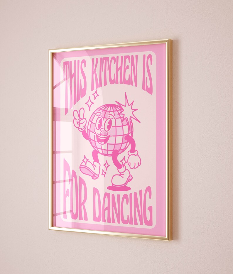 May include: Pink framed poster with a white disco ball character dancing and the text "This Kitchen is for Dancing".