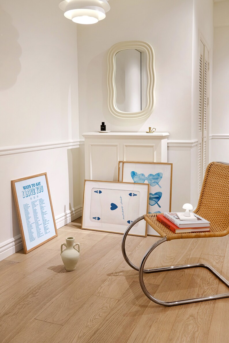 May include: A white room with a white chair, a white cabinet, and three framed prints. The prints are of a playing card, a butterfly, and a list of ways to say "I love you".