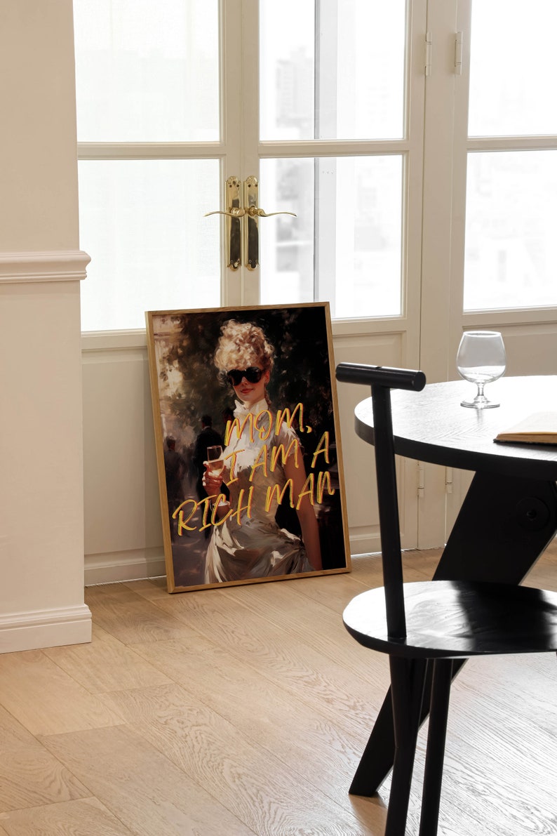 May include: A framed print of a woman in a white dress with sunglasses and a glass of wine. The text "MOM, I AM A RICH MAN" is written in gold lettering on the print.