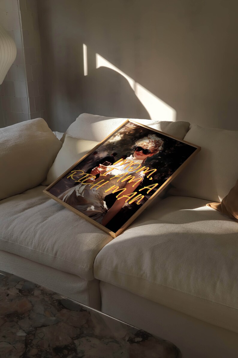May include: A framed print of a woman wearing sunglasses and a white dress, holding a glass of wine. The text "MOM, I AM A RICH MAN" is written in yellow on the print.