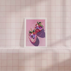 May include: Two pink disco ball strawberries in a white frame against a pink tiled background.