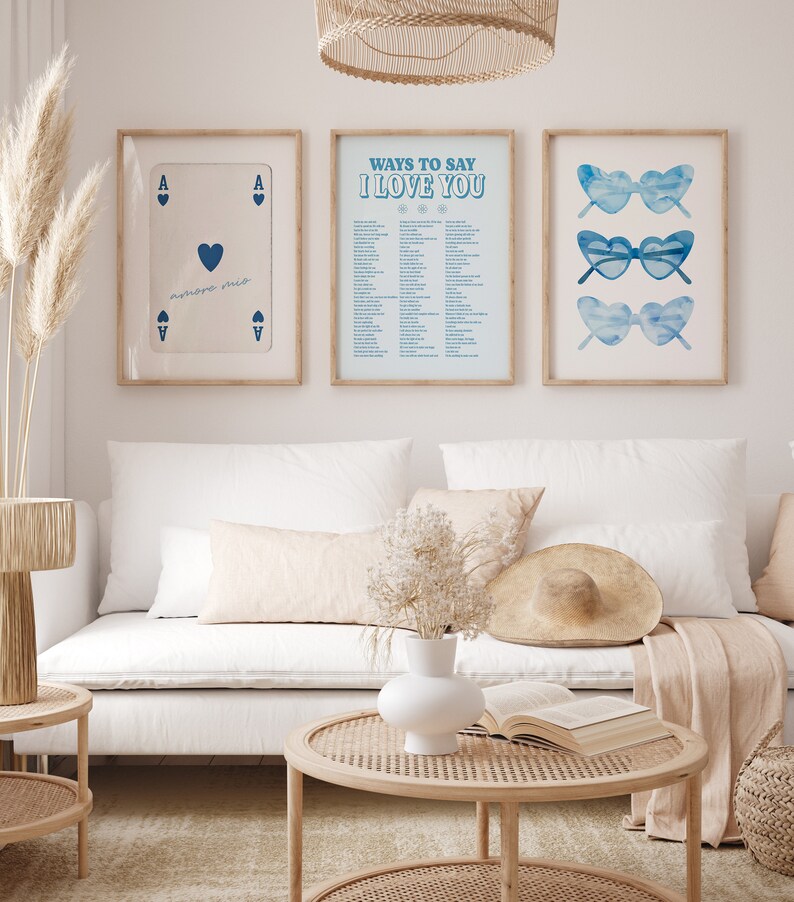 May include: Three framed prints on a white wall. The left print is a blue ace of hearts playing card. The middle print is a light blue background with the text "Ways to Say I Love You" in blue. The right print is a light blue background with three pairs of blue sunglasses.