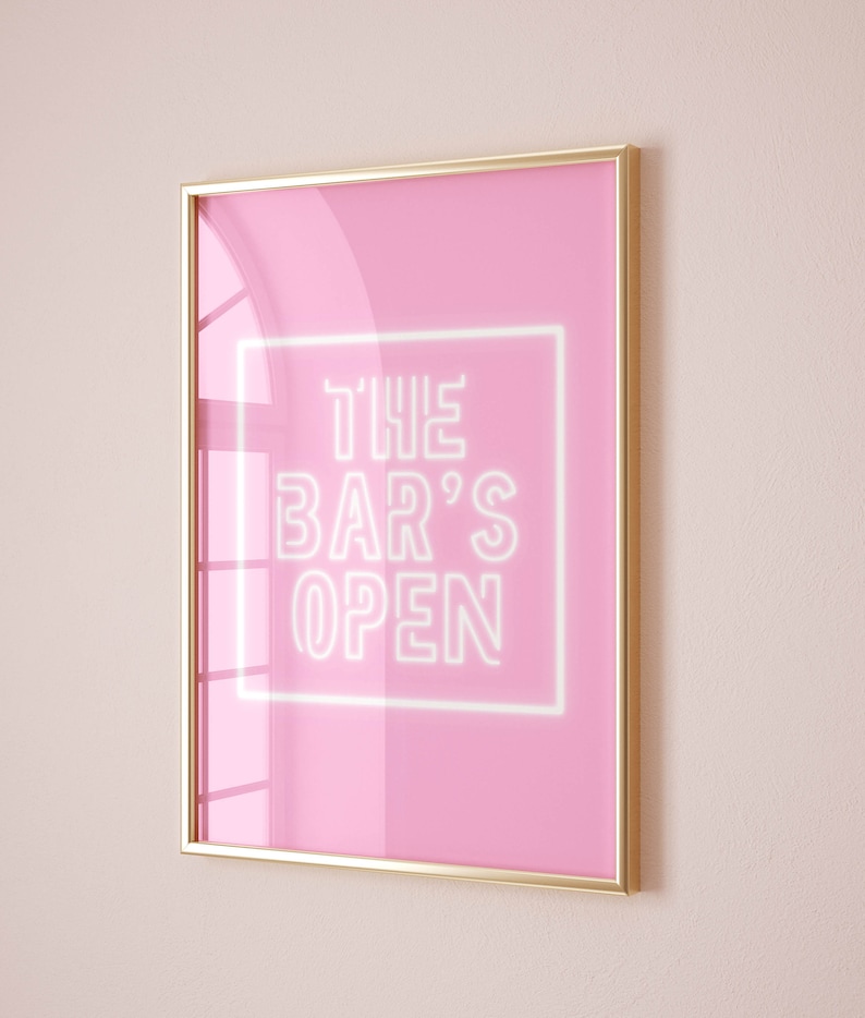 Puede incluir: Un p&oacute;ster rosa enmarcado con un letrero de ne&oacute;n blanco que dice "THE BAR'S OPEN".