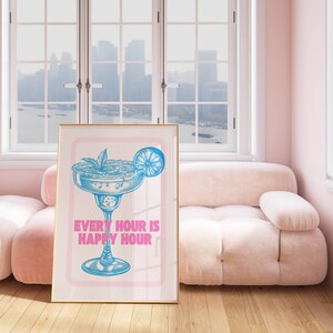 Puede incluir: Una impresi&oacute;n enmarcada con un fondo rosa y una ilustraci&oacute;n azul de una copa de margarita con una rodaja de lima. El texto "EVERY HOUR IS HAPPY HOUR" est&aacute; impreso en rosa debajo del vaso.