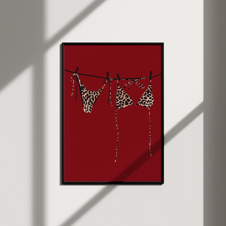 May include: A leopard print bikini hanging on a clothesline against a red background.