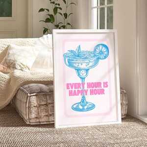 Puede incluir: Una impresi&oacute;n enmarcada en blanco con una ilustraci&oacute;n azul de una copa de margarita con una rodaja de lima y el texto "Every Hour is Happy Hour" en rosa.