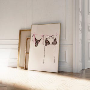 May include: A print of a leopard print bikini hanging on a clothesline with pink string. The print is on a white background.