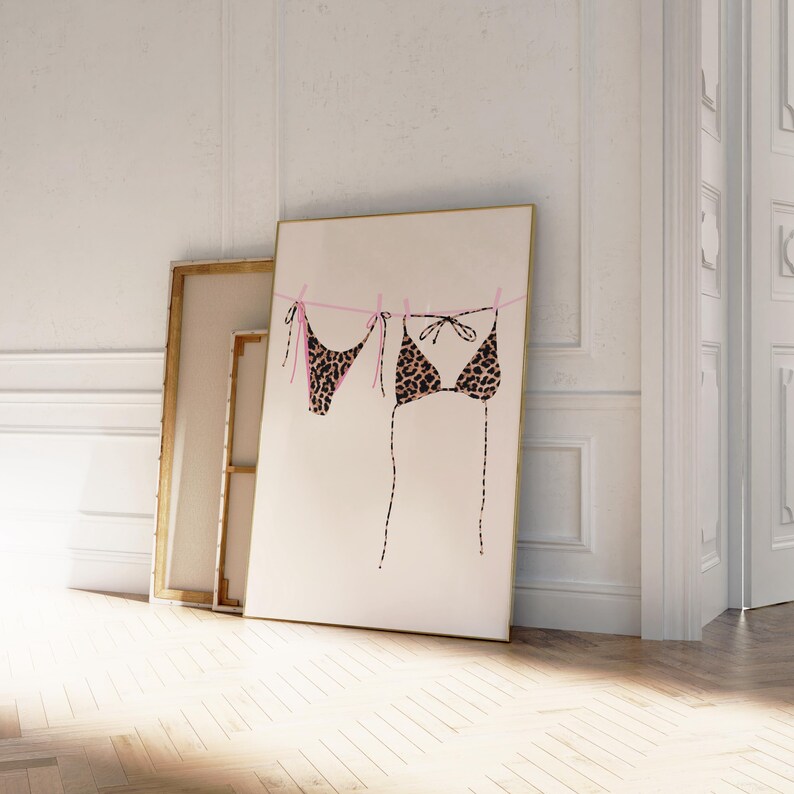May include: A print of a leopard print bikini hanging on a clothesline with pink string. The print is on a white background.