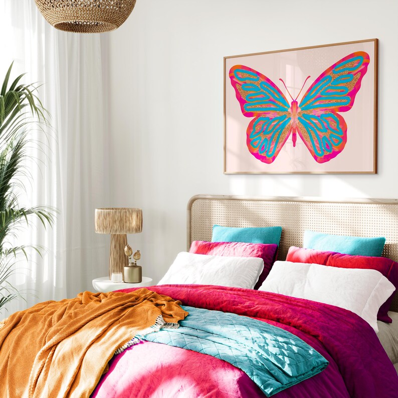 May include: A bedroom with a white bed, a pink duvet, a teal throw blanket, and a large framed print of a pink and blue butterfly on the wall.