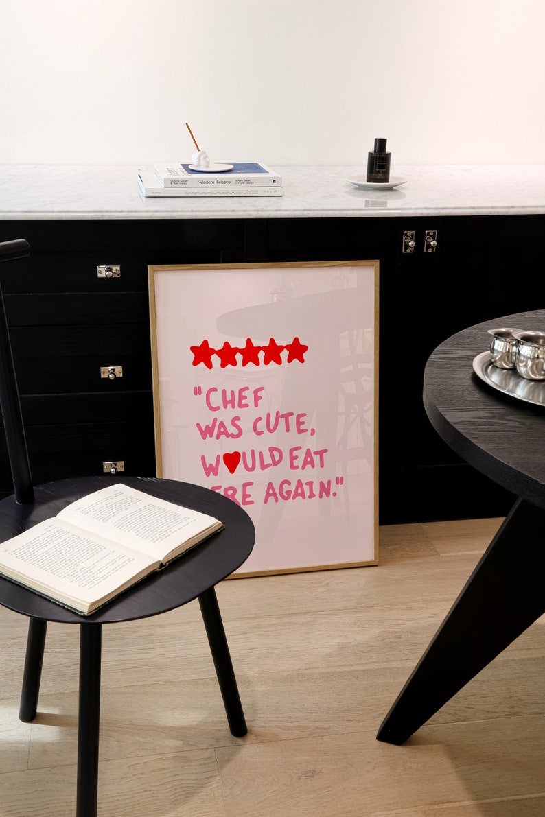 May include: A framed print with a pink background and white text that reads "Chef was cute, would eat here again."  Five red stars are above the text.