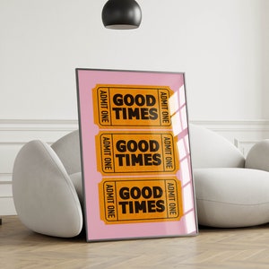 May include: A framed print with a pink background and three orange ticket-shaped designs. Each ticket says "Good Times" in black text and "Admit One" on the sides.