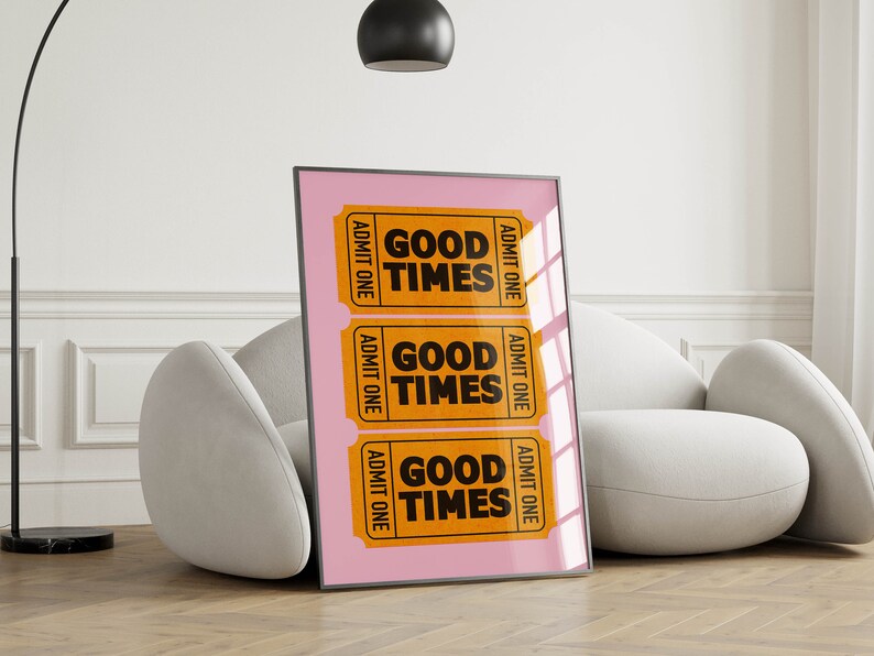 May include: A framed print with a pink background and three orange ticket-shaped designs. Each ticket says "Good Times" in black text and "Admit One" on the sides.