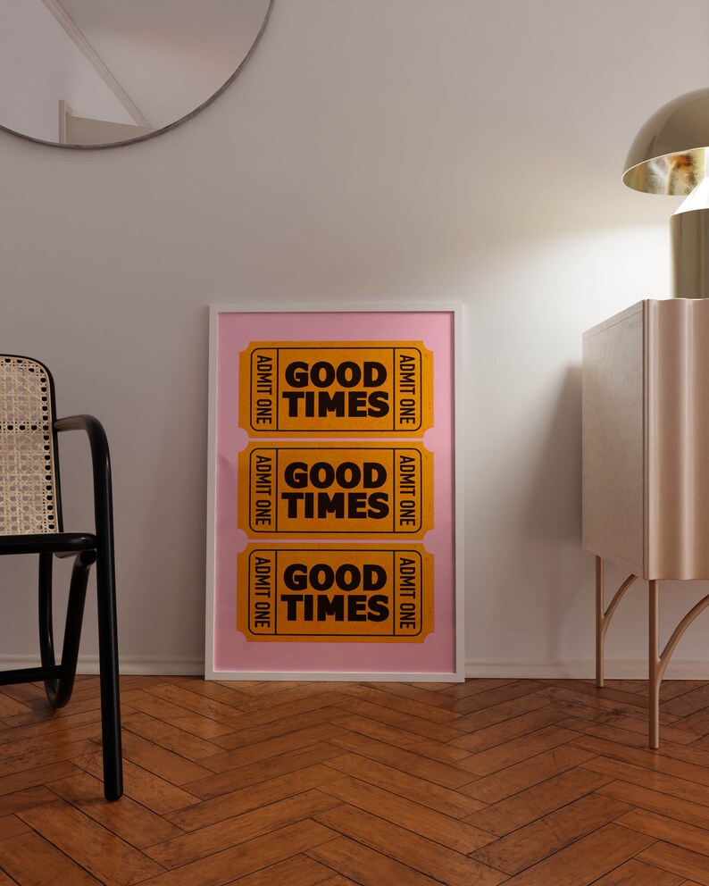 May include: Three yellow ticket-shaped prints with the text "Good Times" in black letters on a pink background. The prints are framed in a white frame.
