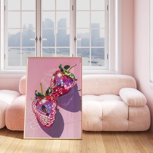 May include: A framed print of two pink disco ball strawberries on a pink background.